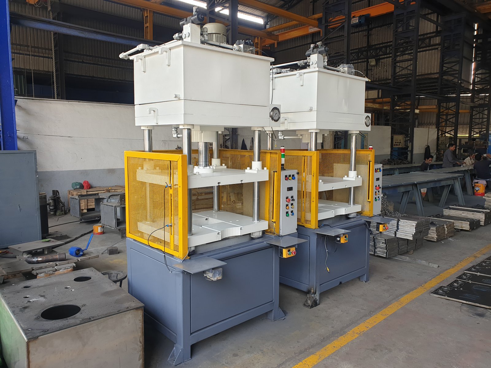 Two Four-Pillar Hydraulic Presses side by side with yellow mesh guarding, Pune manufacturer