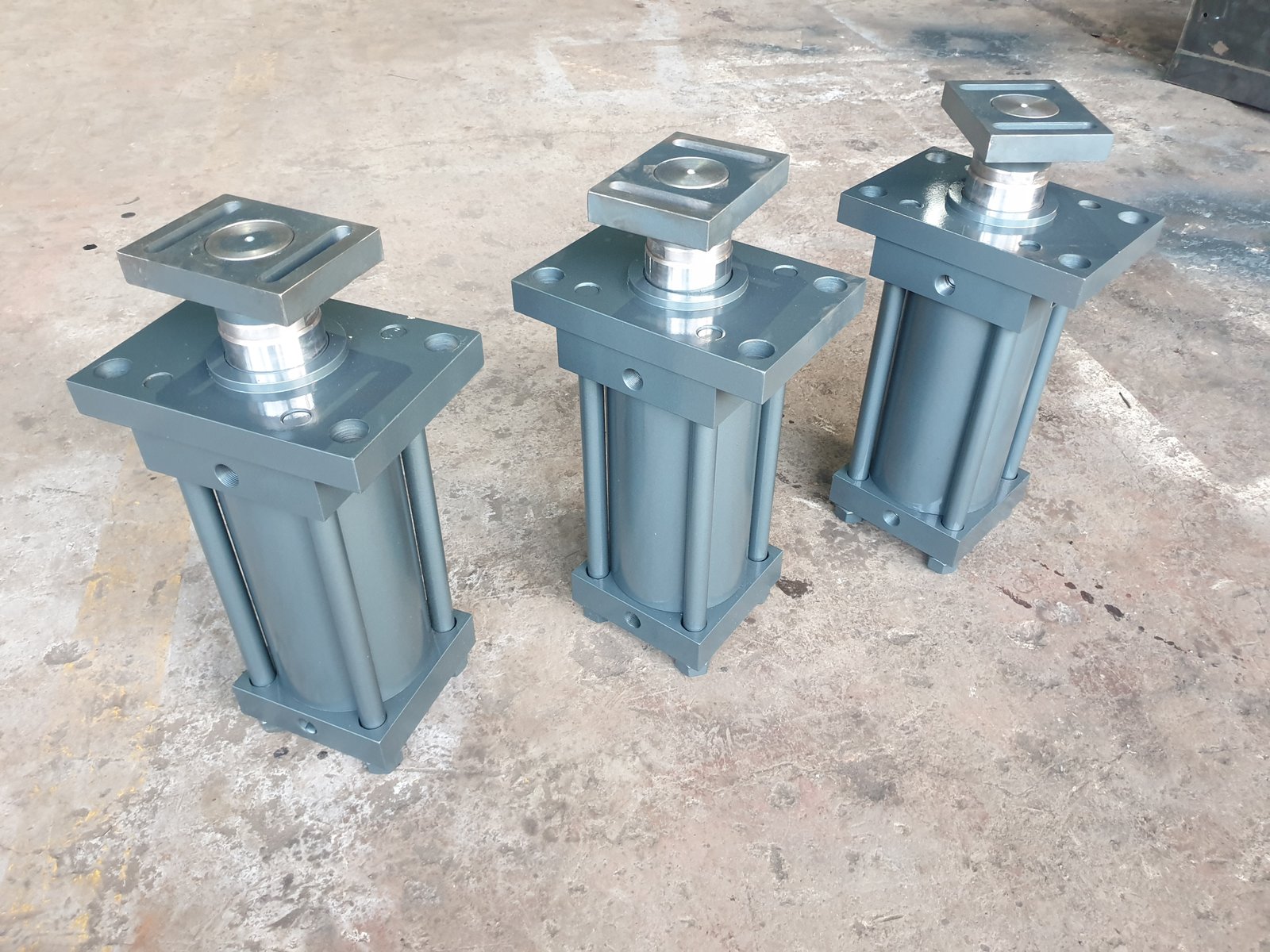 Three tie-rod Hydraulic Cylinders with square mounting plates, manufactured by Desire Hydraulics, Pune