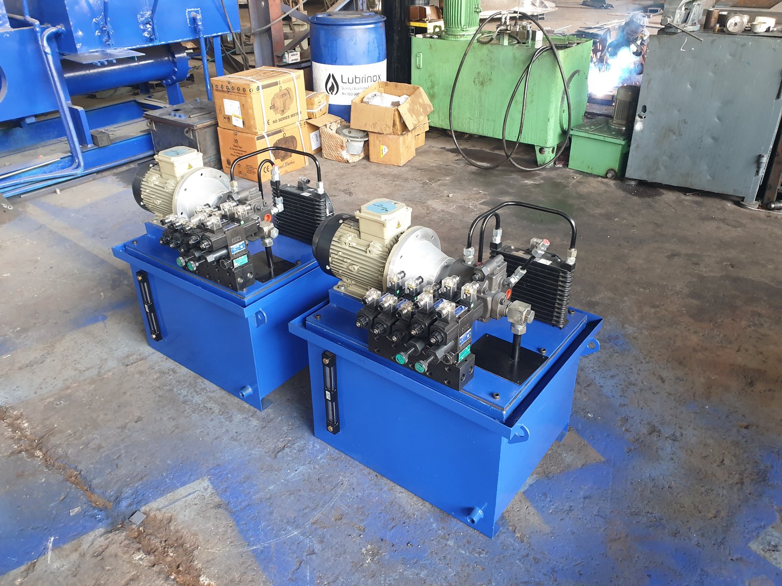 Two blue Hydraulic Power Packs on a factory floor, manufactured by Desire Hydraulics, Pune