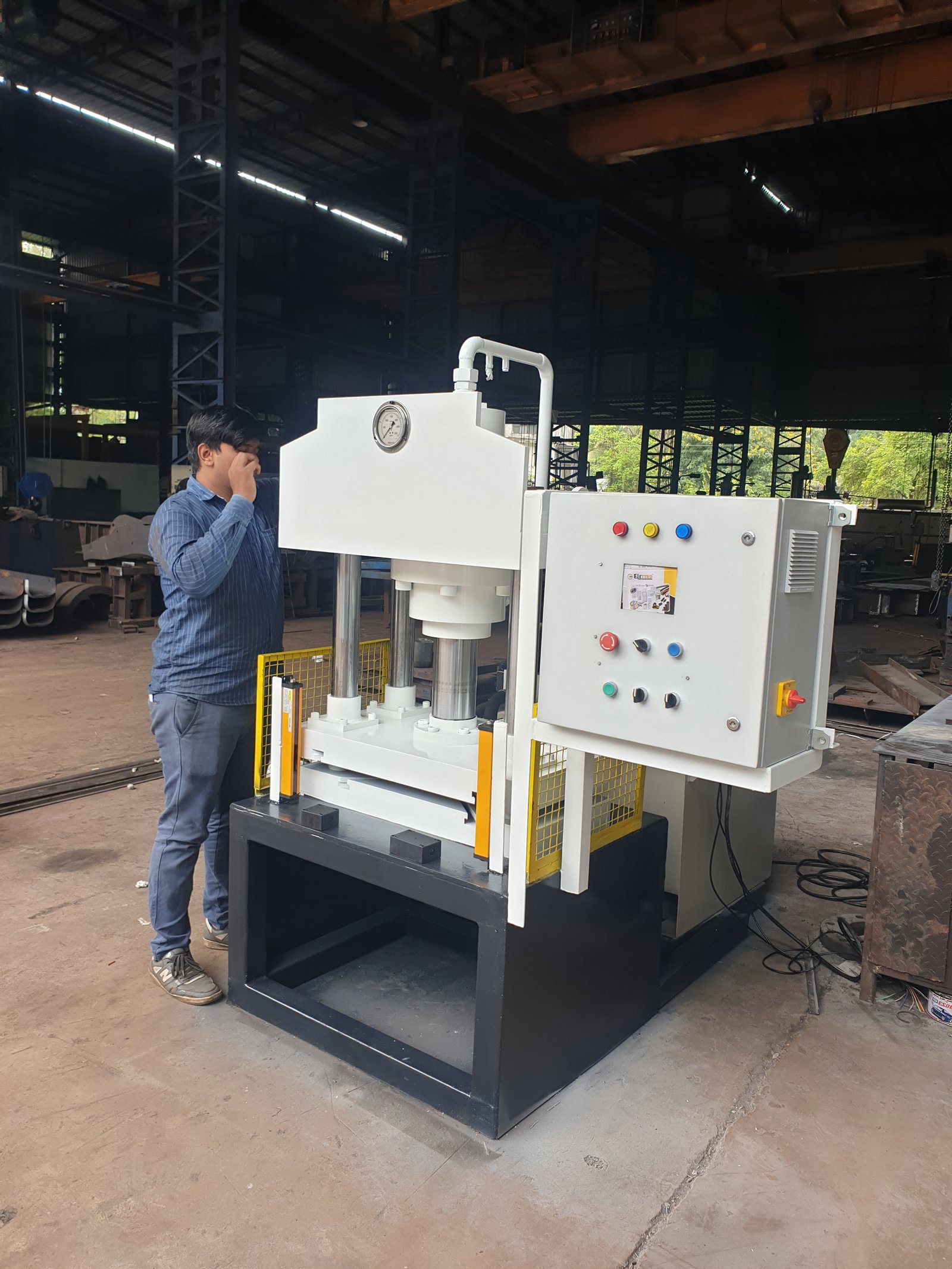 Hydraulic Press Machine with mesh safety guarding and control panel, operator inspecting, Pune